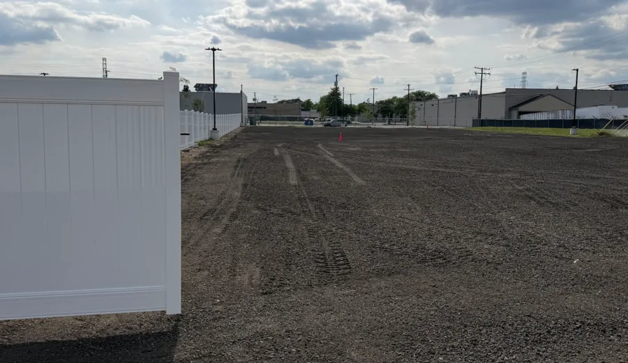 Lot graded to bare soil beside a white fence