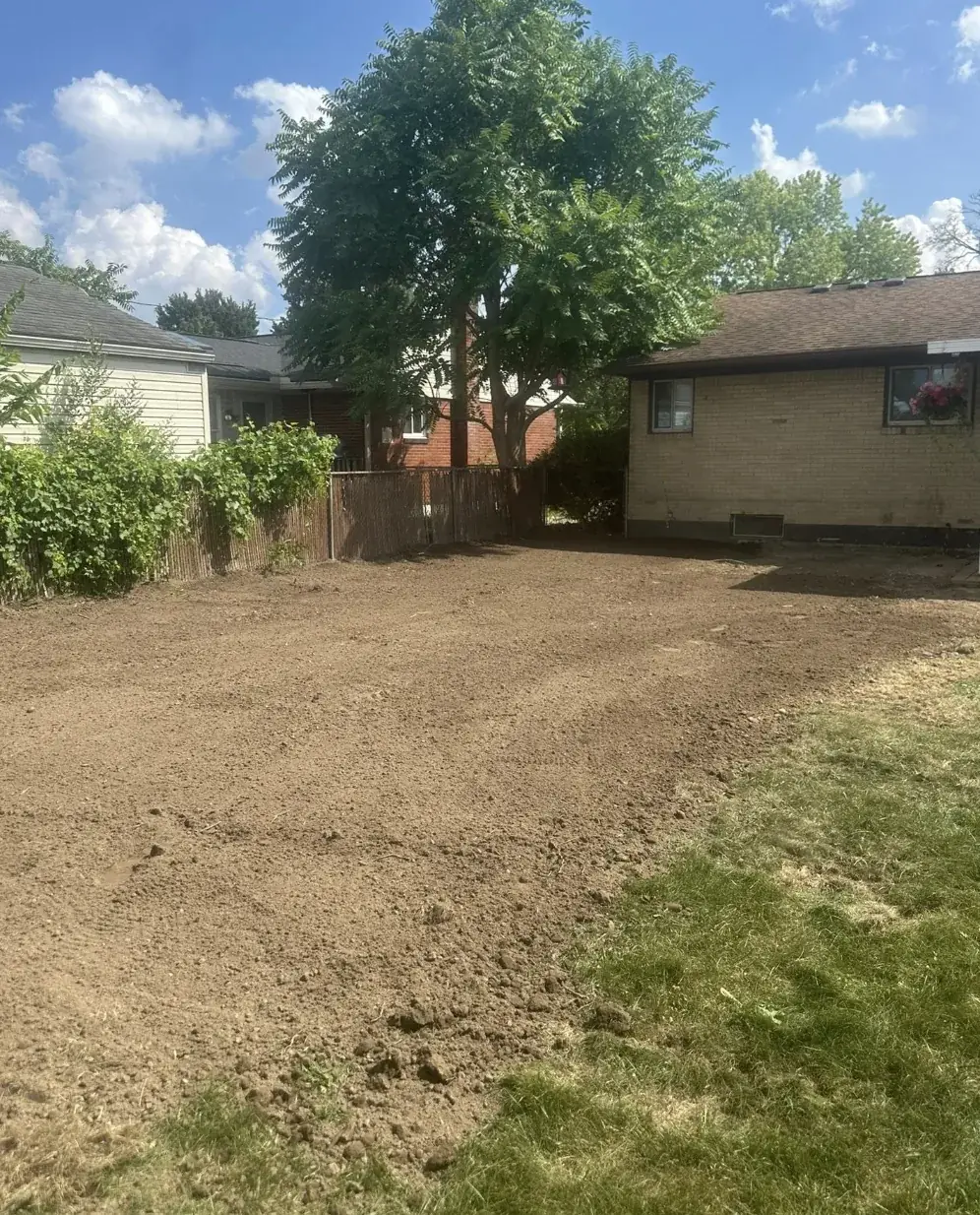 Back yard behind a house cut down to bare, graded soil