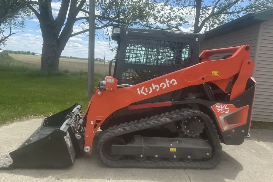 Track loader on a drive cut down to its base beside a house