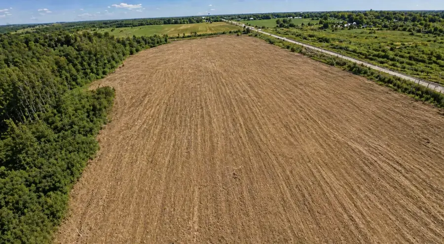 Aerial view of a long field worked down to bare soil between treelines