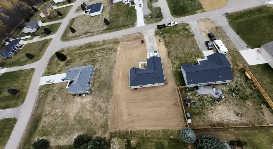 Aerial view of a cleared and graded lot between houses on a residential street