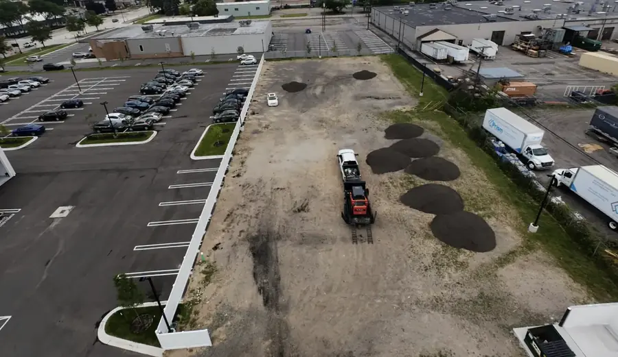 Aerial view of a parking lot extension being graded beside a paved lot