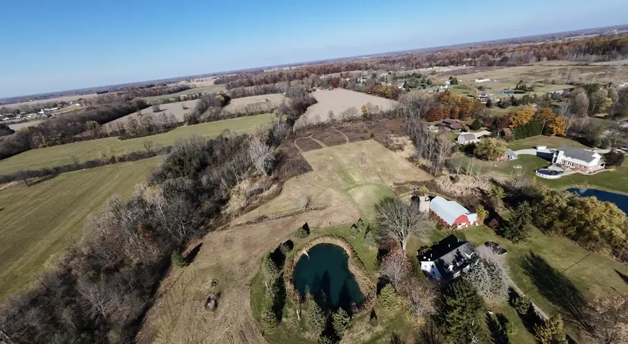 Aerial view of a pond property with the brush cleared back across the field