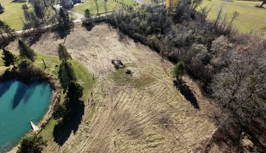 Aerial view of cleared ground around a pond with fields beyond