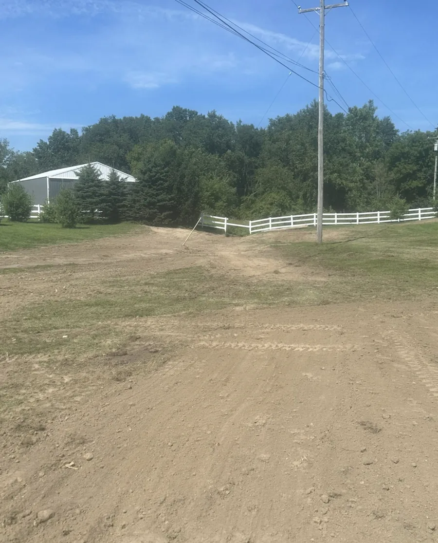 Graded dirt area beside a white fence